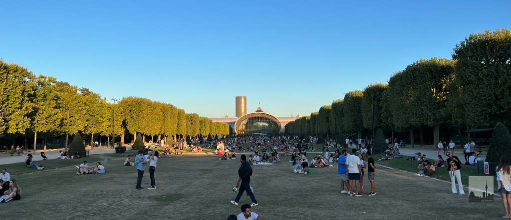 Hundreds of people enjoying their evening between Eiffel Tower and Grand Palais Éphémère. Picknick around Champ de Mars in Paris